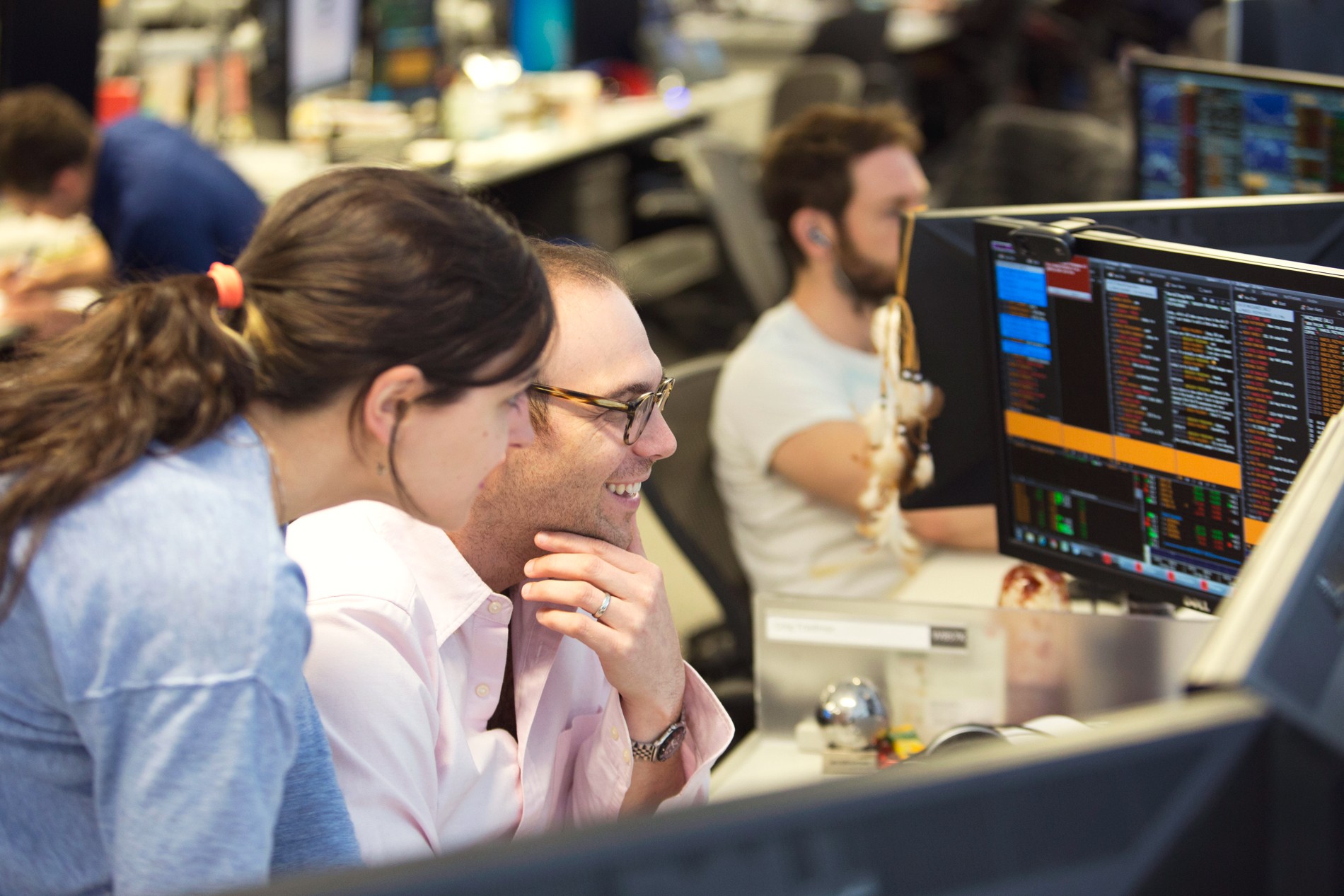 Two investment professionals on a trading floor discuss a trade.